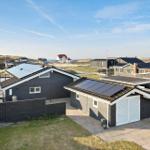 Modern vacation home with solar panels and terrace. View of dunes and holiday homes.