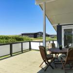 Terrace with table and chairs, view of greenery and houses.