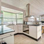 Kitchen with countertops, stove, and windows. Dining area with table and chairs.