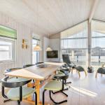 Large room with dining table, chairs, and seating. Large windows and wooden ceiling.