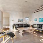 Living room with wooden walls, sofa, table, and chair. Passage to the bedroom.