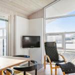 Dining area with table, chairs, and TV. Large windows overlook the terrace.