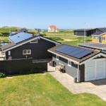 A modern house with solar panels, terrace, and garden. View of the coast.