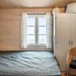 Schlafzimmer mit Holzwand, Bett, Schrank und Stuhl.