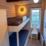 Ein Schlafzimmer mit Doppelstockbett, Fenster und Stuhl.