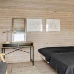 Schlafzimmer mit Holzwand, Bett, Schreibtisch und Spiegel.