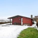 Rotes Holzhaus mit Schneeflächen, Gartenbank und Tisch unter Dach.