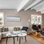Wohnzimmer mit Sofa, Sitzgelegenheit und Kamin. Holzboden und weiße Deckenbalken.