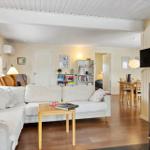 Wohnzimmer mit Sofa, Kamin und Essbereich. Holzboden und weiße Wände.