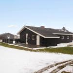 Schwarzes Ferienhaus mit Terrasse und Schnee im Vordergrund.