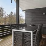 Terrasse mit Tisch und Stühlen, Blick auf Wald und Himmel.