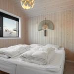 Bedroom with wooden walls, large window, and white bed.