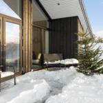 Winter terrace with seating and snow cover in front of modern house.