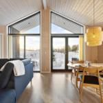 Living and dining area with wooden ceiling, large windows, and snowy view.