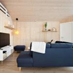 Living room with blue sofa, TV, and wood-paneled walls.