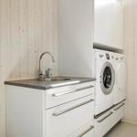 Waschraum mit Waschmaschine, Trockner und Spüle an Holzwand.