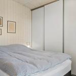 Schlafzimmer mit Bett, Kleiderschrank und Holzwand