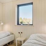 Zwei Betten mit weißen Bettwäsche, Holzwände und Fenster mit Blick auf Bäume.