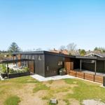 Moderne Villa mit Holzverkleidung, Garten und Terrasse unter klarem Himmel.