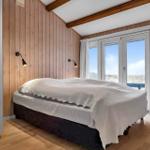 Schlafzimmer mit Bett, Holzwand und Fenster zur Aussicht.