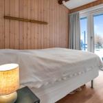 Schlafzimmer mit Bett, Holzwand und Fenster zur Aussicht.