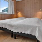 Schlafzimmer mit Bett, Holzwand und Fenster. Zwei Wandlampen und Heizkörper sind sichtbar.