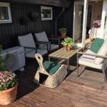 Terrasse mit Sitzgruppe, Tisch und Pflanzen. Durchgang ins Innere.