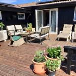 Terrasse mit Sitzgelegenheiten und Pflanzen vor einem Haus mit Schiebetüren.