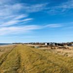 Strandnahe Ferienwohnung mit Blick aufs Meer und grünen Hang.