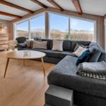 Wohnzimmer mit großem Sofa, Holzboden und Blick aufs Wasser und Gras.