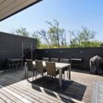 Deck with table, chairs, and grill under open sky.