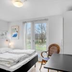 Bedroom with bed, desk, chair, and window with view.