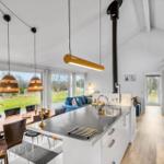 Kitchen with dining area and garden view. Wooden floor, white cabinets, and black countertop.