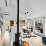 Modern open kitchen, dining area, and living room with fireplace and large window area.