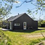 Modern dark-clad cabin with white windows and terrace in the green.