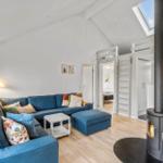 Living room with blue sofa, fireplace, and sloped ceiling. Stairs lead to upper level.