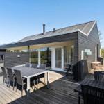 Modern villa with terrace, seating, and garden. Glass doors lead inside.