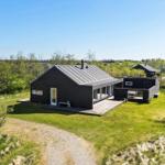 Modern wooden cabin with terrace and garden in green surroundings.