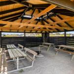 View of a covered area with wooden benches and grill spot.
