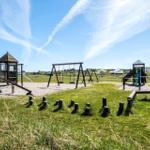 Large playground with slides, swings, and climbing frames on sandy ground.