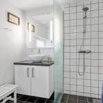 Bathroom with shower, sink and window. Tiles and white walls.