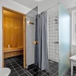 Bathroom with shower, sauna, and window with chair.
