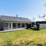 Modern wooden cabin with terrace and garden. Large glass front. Outdoor table with chairs.