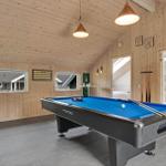 Room with pool table, wooden walls and windows. Bathroom and fireplace in background.