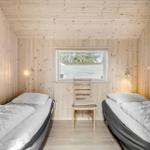 Two single beds, wooden walls, chair and window with view outside.