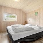 Bedroom with wooden paneling, bed, and window.