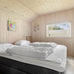 Bedroom with wooden walls, bed, and window with view outside.