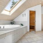Bath with whirlpool, sauna, and shower under wooden ceiling with skylight.