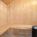 Sauna with wooden walls and bench. Stones in the heater.