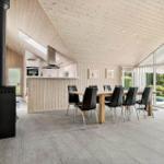Large dining area with wooden table and chairs, kitchen, and terrace with glass doors.